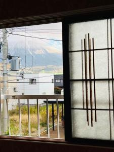 a window with a view of a building and mountains at NisekoSnowHouse in Abuta