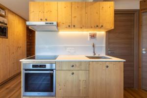 a kitchen with wooden cabinets and a stove top oven at La Foret du Praz 501 in Courchevel