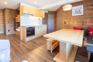 a kitchen with wooden walls and a wooden table at La Foret du Praz 501 in Courchevel