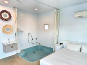 a bathroom with a shower and a bed and a sink at Kenting South Border DeSign Hotel in Eluan