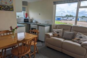 een woonkamer met een bank en een tafel bij 2 Bed Chalet - Sleeps 5 - Free Parking - Tv in Great Yarmouth