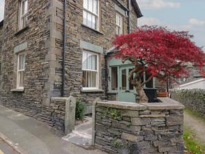 een bakstenen huis met een rode boom ervoor bij Park View in Ambleside