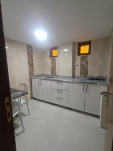 Un baño con armarios blancos, una mesa y un espejo. en DENİZ BAYAN PANSİYON APARt, en Sivas