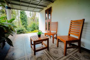 two wooden chairs and a table in a room at Anvitha Mansions in Attigundi