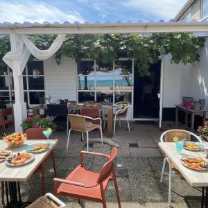 un patio con mesas y sillas y vistas al océano en Beach Stay 1 Min Walk, en Zoutelande
