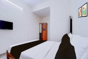 a white bedroom with a white bed and a tv at Hotel O Kallar Vattiyar Waterfalls Munnar in Munnar