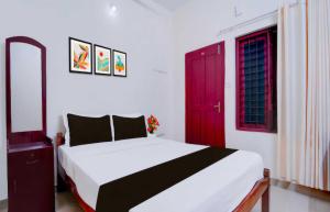 a bedroom with a bed and a red door at Hotel O Kallar Vattiyar Waterfalls Munnar in Munnar +11 photos