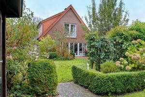 BübbensにあるFerienhaus Pothの茂みと木々の庭園のある家