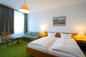 una camera d'albergo con un letto e un divano di Hotel Arcus a Elsterwerda