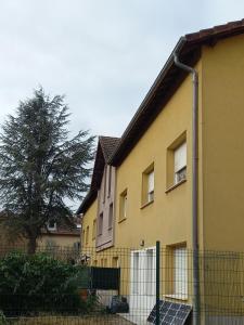 une maison jaune avec une clôture devant elle dans l'établissement Les appartements du Lion de Belfort, à Belfort