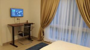 a bedroom with a desk and a tv and a window at Big 1 Bedroom Apartment at Cantonments - Pool, Gym, Game Room in Accra +24 photos