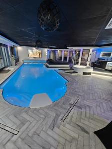 a large swimming pool with blue water in a building at Bed & Wellness Malina deluxe in Lelystad +9 photos