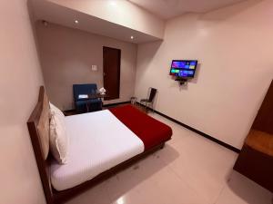 Un dormitorio con una cama y un televisor en una pared. en Hotel SK Galaxy Thane West, en Thane