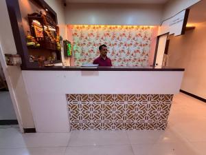 Un hombre de pie detrás de un mostrador en un restaurante. en Hotel SK Galaxy Thane West, en Thane