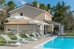 a pool with chairs and umbrellas next to a house at Villa Silvia in Montemaggiore al Metauro