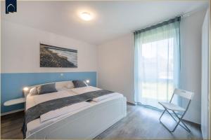 a bedroom with a bed and a chair and a window at Ferienanlage Sonneninsel Haus Himmelblau Erdgeschoss in Loddin