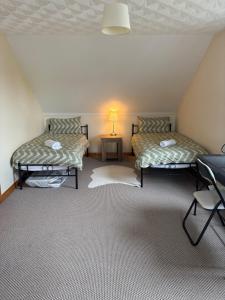 Zimmer im Dachgeschoss mit 2 Betten und einem Tisch in der Unterkunft Moyle Manor in Ballycastle