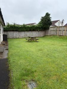 einen Picknicktisch in einem Garten neben einem Zaun in der Unterkunft Moyle Manor in Ballycastle