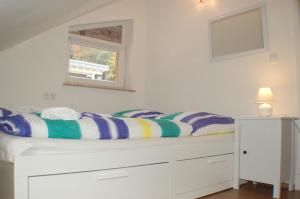 ein weißes Schlafzimmer mit einem Bett und einem Fenster in der Unterkunft Wacholder am Waldsee 2 in Rieden