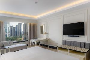 a hotel room with a bed and a flat screen tv at Mangkuluhur ARTOTEL SUITES in Jakarta