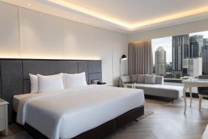 a bedroom with a large white bed and a couch at Mangkuluhur ARTOTEL SUITES in Jakarta
