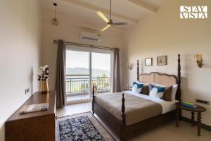 a bedroom with a bed and a large window at StayVista at Raga Living - Mountain Views, Bonfire in Parwanoo
