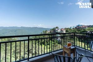 a balcony with a table and chairs and a view at StayVista at Raga Living - Mountain Views, Bonfire in Parwanoo