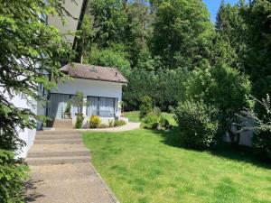 a garden with a white house and a lawn at Bezauberndes Gästehaus im Grünen mit Terrasse in Bad Wildbad