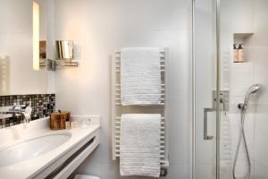 Un baño blanco con lavabo y ducha. en Serotel Suites Opera, en París