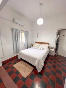 a bedroom with a white bed and a checkered floor at Departamentos DCB in Capilla del Monte