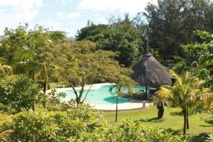 a resort with a swimming pool and a straw umbrella at Kenville in Cap Malheureux