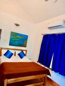 a bedroom with a bed with blue pillows at Sana Villa & Resort Anjuna Beach Goa in Anjuna