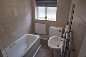 a bathroom with a tub and a toilet and a sink at The Granary Cottages  +14 photos