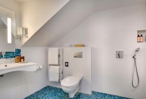 Un baño blanco con inodoro y lavabo. en Serotel Suites Opera, en París
