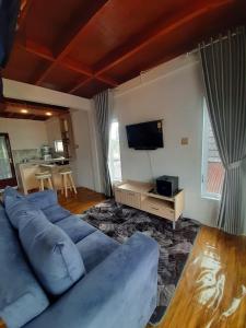 a living room with a blue couch and a television at Villa Castanea Dieng in Diyeng