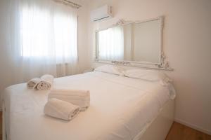 a white bed with towels on it with a mirror at Solemar Sicilia - Casa Minerva in Santa Flavia