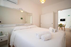 a bedroom with a white bed with a large mirror at Solemar Sicilia - Casa Minerva in Santa Flavia