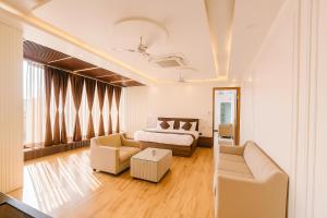 a bedroom with a bed and a couch and chairs at Mangalam Inn in Lucknow +13 photos