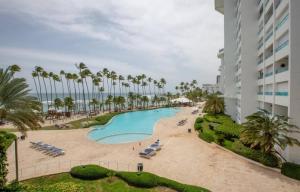 - une piscine avec des chaises longues et des palmiers à côté d'un bâtiment dans l'établissement Beachfront Apartment Marbella, Juandolio, à Villas del Mar