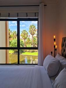 a bedroom with a window with a view of palm trees at Island Club by Smart City Stays in Cape Town +20 photos