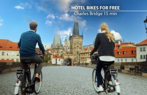 a man and woman riding bikes down a city street at Hotel Uno Prague in Prague