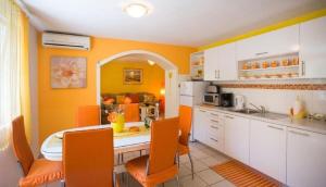 una cocina con armarios naranjas y blancos y una mesa. en Apartment Zelja, en Orebić