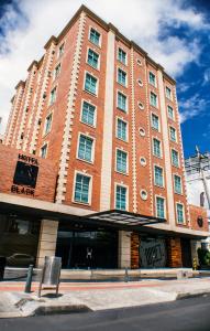 un gran edificio de ladrillo rojo con un cartel delante en Hotel Black Usaquen, en Bogotá