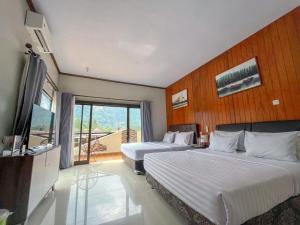a hotel room with two beds and a television at Gubuk Ndeso Bromo in Bromo