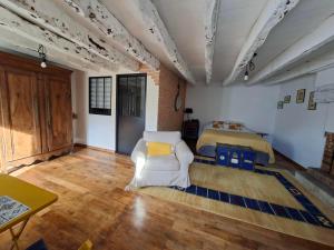 a living room with a bed and a white chair at Gîte de la croix in La Croix-Helléan