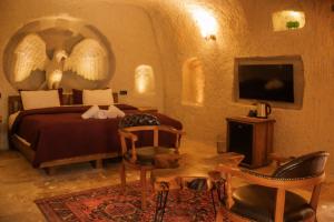 Un dormitorio con una cama, un televisor y sillas. en Rose Moon Cave, en Nevşehir