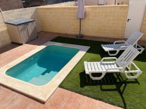 two chairs and a swimming pool with two chairs and a table at Villas Privadas EL DESCANSO in La Rinconada