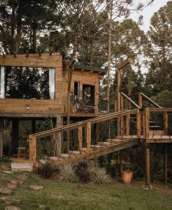a tree house with a wooden staircase in a yard at Cabana na Tree in Urubici