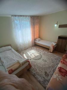 une petite chambre avec deux lits et une fenêtre dans l'établissement Issyk-Kul Cozy Cottage, à Rybpunkt