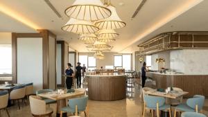 un restaurant avec des tables et des chaises et des gens debout à un bar dans l'établissement Apec Mandala Wyndham ChamBay Mui Ne - LT, à Ấp Thiẹn Ái